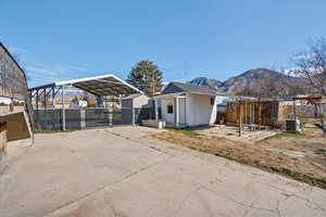 Back of house with a carport, concrete driveway, a patio, and a mountain view