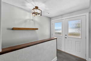 Doorway featuring a textured ceiling, wood finished floors, and french doors