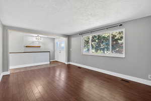 Unfurnished living room with wood finished floors and a textured ceiling