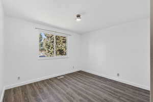 Spare room featuring baseboards and dark wood-style floors