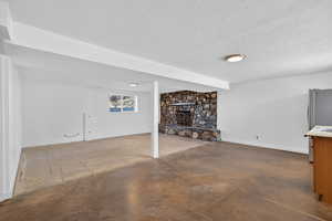 Basement featuring a fireplace, a textured ceiling, and freestanding refrigerator