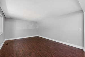 Bonus room with dark wood finished floors and baseboards
