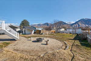 Fenced backyard with a patio, a fire pit, a mountain view, and a storage unit