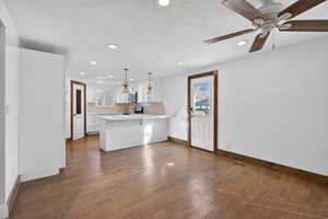Kitchen featuring white cabinetry, dark wood finished floors, decorative backsplash, a breakfast bar area, and a peninsula
