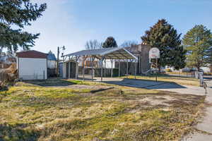 View of yard featuring a storage shed, a carport, basketball court, and concrete driveway