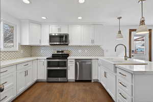 Kitchen featuring healthy amount of natural light, stainless steel appliances, a peninsula, white cabinets, and a textured ceiling
