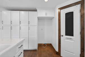 Kitchen featuring white cabinets, light stone countertops, and dark wood-style floors