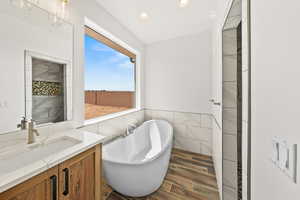 Bathroom featuring vanity, tile walls, a freestanding tub, wood tiled floors, and recessed lighting