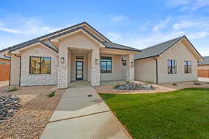 View of front of house featuring stucco siding, stone siding, a front lawn, and a tile roof