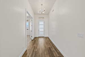 Doorway with wood finished floors and suspended lighting