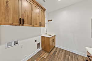 Laundry room featuring wood finish floors, hookup for an electric dryer, cabinet space, and washer hookup