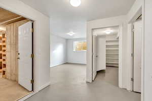 Hallway with concrete flooring and baseboards