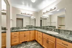 Full bath featuring double vanity and stone finish floors