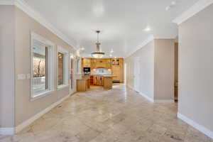 Kitchen featuring glass insert cabinets, ornamental molding, a center island, hanging light fixtures, and open floor plan