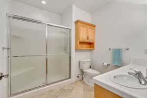 Full bath with a stall shower, double vanity, and recessed lighting