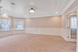 Empty room with a decorative wall, wainscoting, crown molding, recessed lighting, and carpet flooring