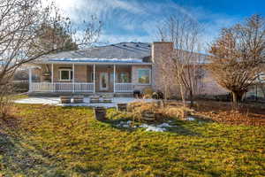 View of front of property with covered porch, a front lawn, and a patio