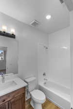 Bathroom featuring washtub / shower combination, vanity, and light wood-style floors