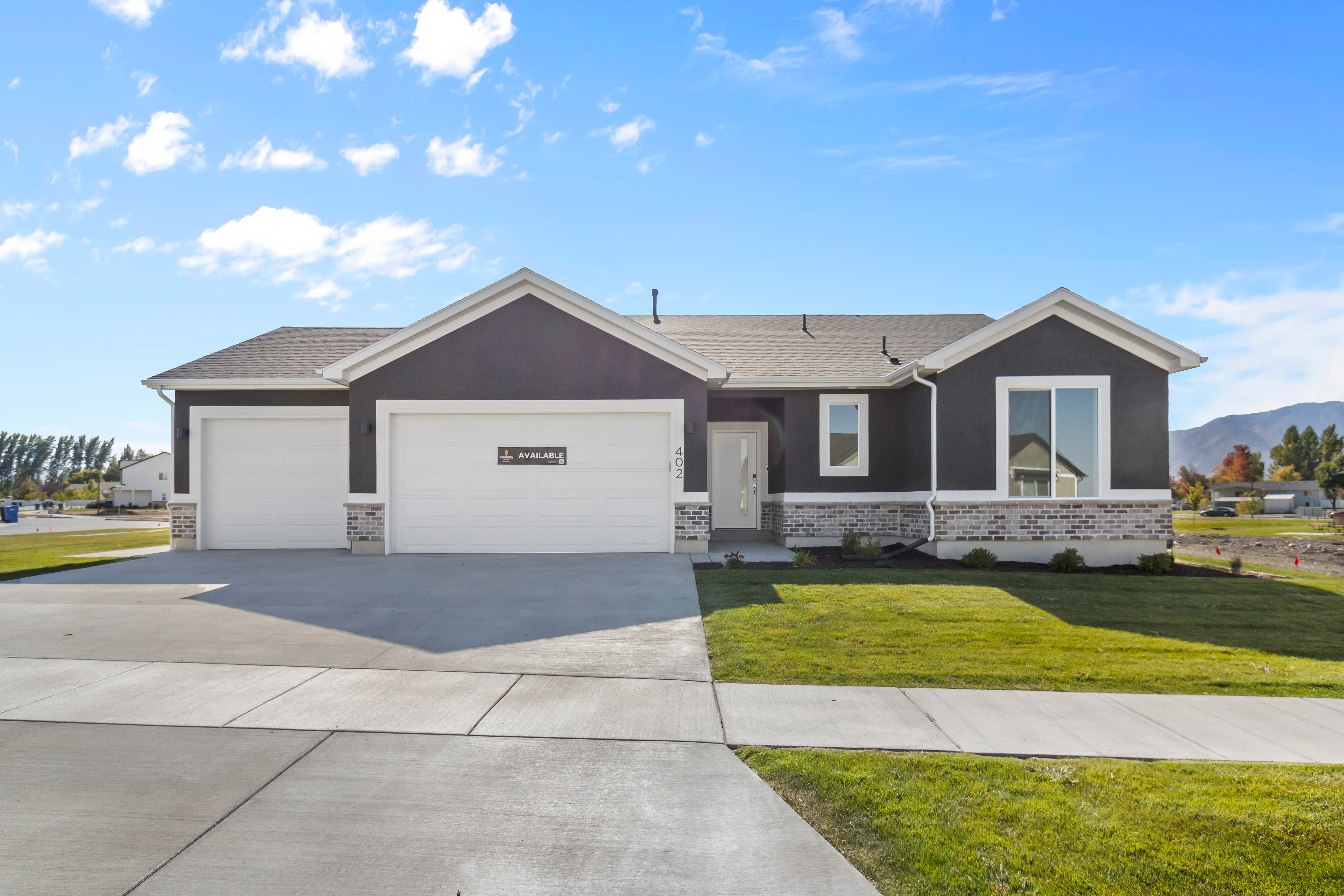Ranch-style house with a front lawn, driveway, brick siding, a garage, and roof with shingles
