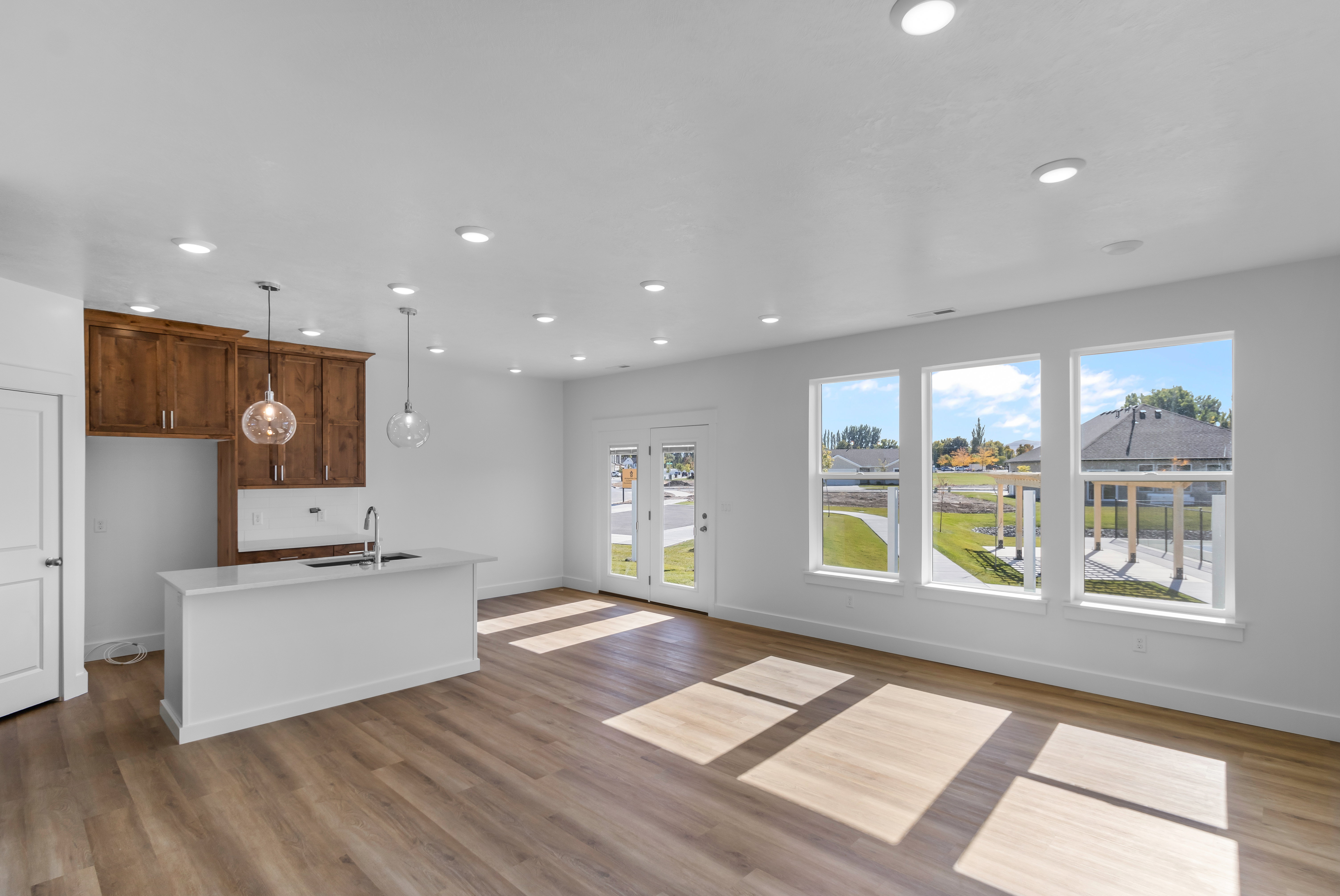 Kitchen featuring decorative light fixtures, a kitchen island with sink, open floor plan, light wood-type flooring, and wood finish cabinets