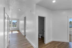 Hallway with light wood-style floors, recessed lighting, and a textured ceiling