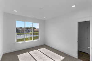 Carpeted spare room with a residential view and recessed lighting