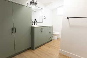 Full bathroom with light wood finished floors, vanity, and lofted ceiling