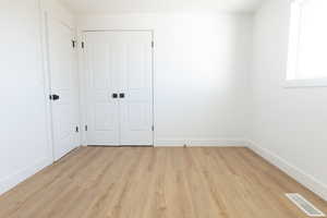 Unfurnished bedroom featuring light wood-style floors and a closet