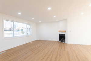 Unfurnished living room featuring recessed lighting, light wood-type flooring, and a fireplace