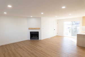 Unfurnished living room featuring light wood finished floors, recessed lighting, and a fireplace