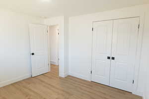 Unfurnished bedroom featuring light wood-type flooring and a closet