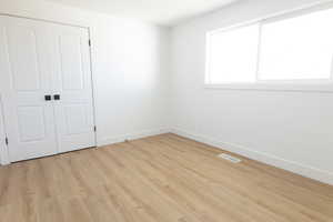 Unfurnished bedroom featuring light wood-type flooring and a closet