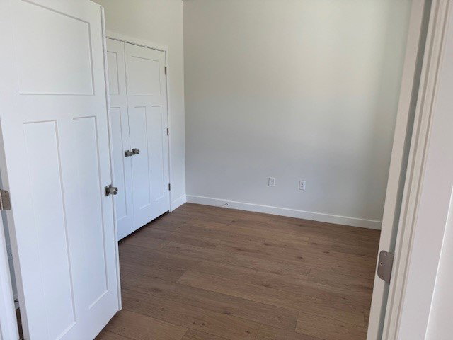 Unfurnished bedroom featuring dark wood-style floors and a closet