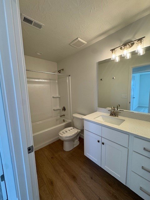 Bathroom featuring vanity, dark wood-type flooring, tub / shower combination, and a textured ceiling
