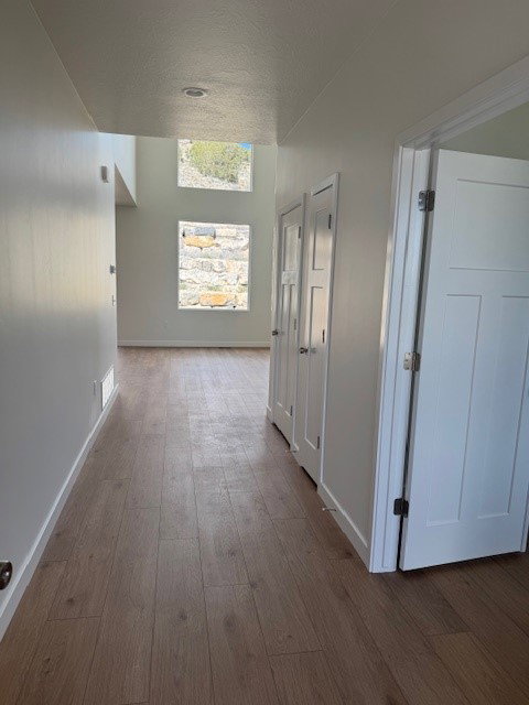 Hallway with dark wood-type flooring and a textured ceiling