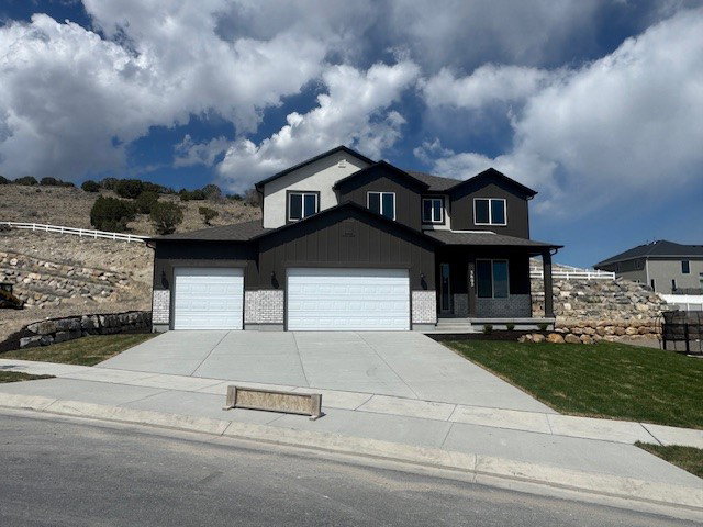 View of front of house with covered porch, an attached garage, concrete driveway, and a front lawn