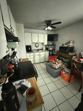 Kitchen with white cabinetry, electric range oven, black microwave, ceiling fan, and light tile patterned flooring