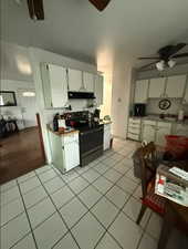 Kitchen with a ceiling fan, electric range, white cabinets, and light tile patterned floors
