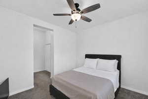 Bedroom with dark colored carpet and a ceiling fan