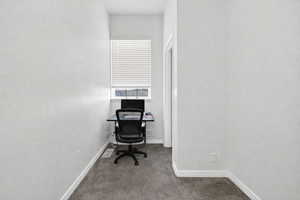 Office space featuring baseboards and dark carpet
