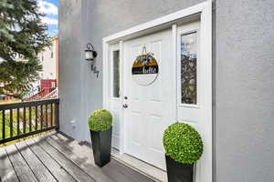 Doorway to property featuring stucco siding and a deck