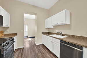 Kitchen with dishwasher, white cabinetry, dark wood-style flooring, and black / electric stove