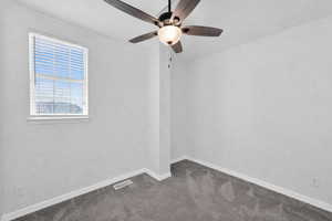 Empty room with dark colored carpet and ceiling fan