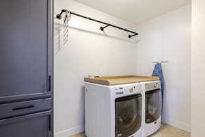 Laundry room with washer and clothes dryer and light tile patterned floors