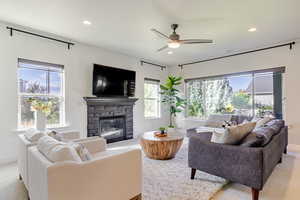 Living area featuring a fireplace, ceiling fan, recessed lighting, and light carpet