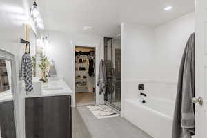 Bathroom with a spacious closet, double vanity, a stall shower, a bath, and light tile patterned floors