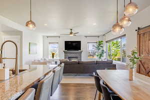 Kitchen featuring pendant lighting, a barn door, dark wood-style flooring, light stone counters, and a fireplace