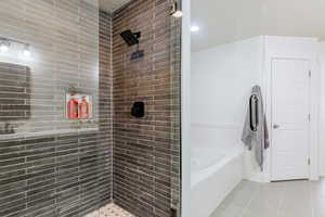 Bathroom featuring a garden tub, a tile shower, and light tile patterned floors