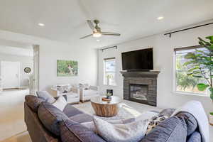 Living room with carpet, a ceiling fan, a fireplace, and recessed lighting