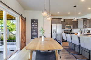 Dining space featuring a barn door, dark wood finished floors, and recessed lighting